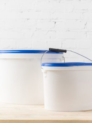 two plastic buckets with paints on wooden surface